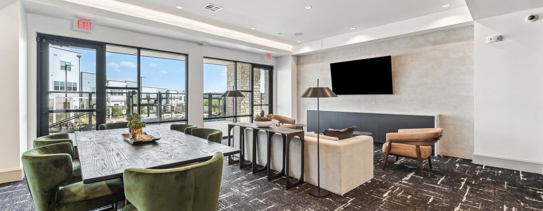 Cutting-edge amenities at your fingertips a clubhouse room with a table, chairs, a couch and a tv